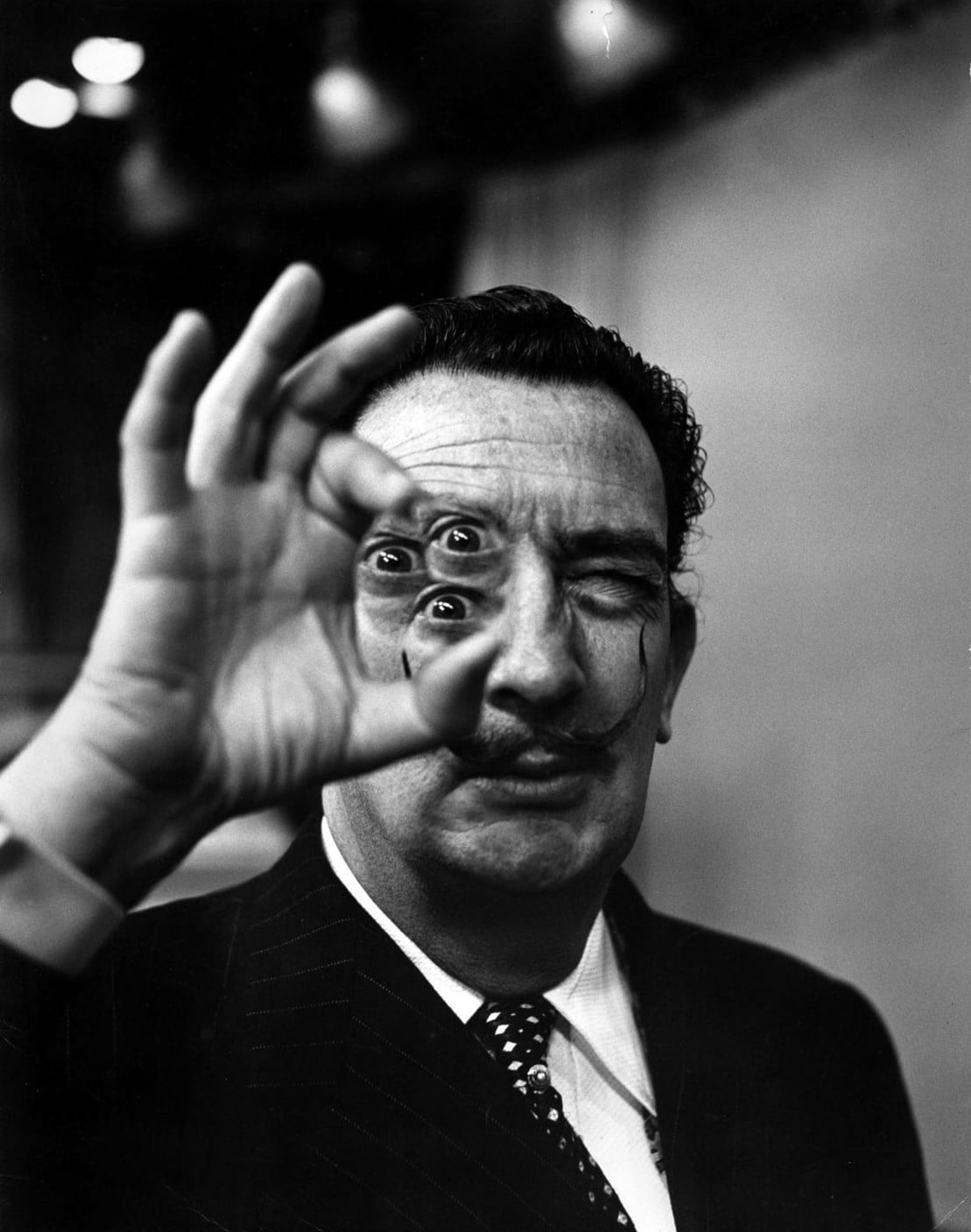 Salvador Dalí mirant a través d'una mà amb un ull visible